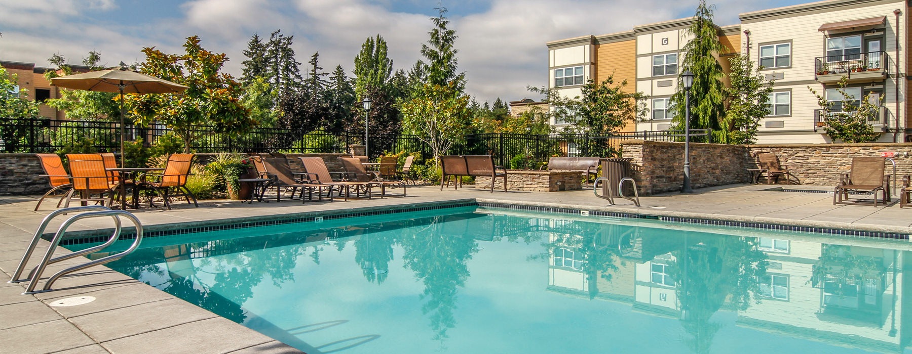 large pool area next to fire pit. table and chairs scattered around